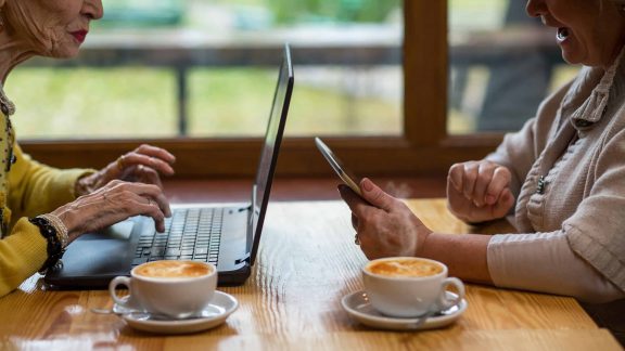 Seniors drinking coffee while on devices